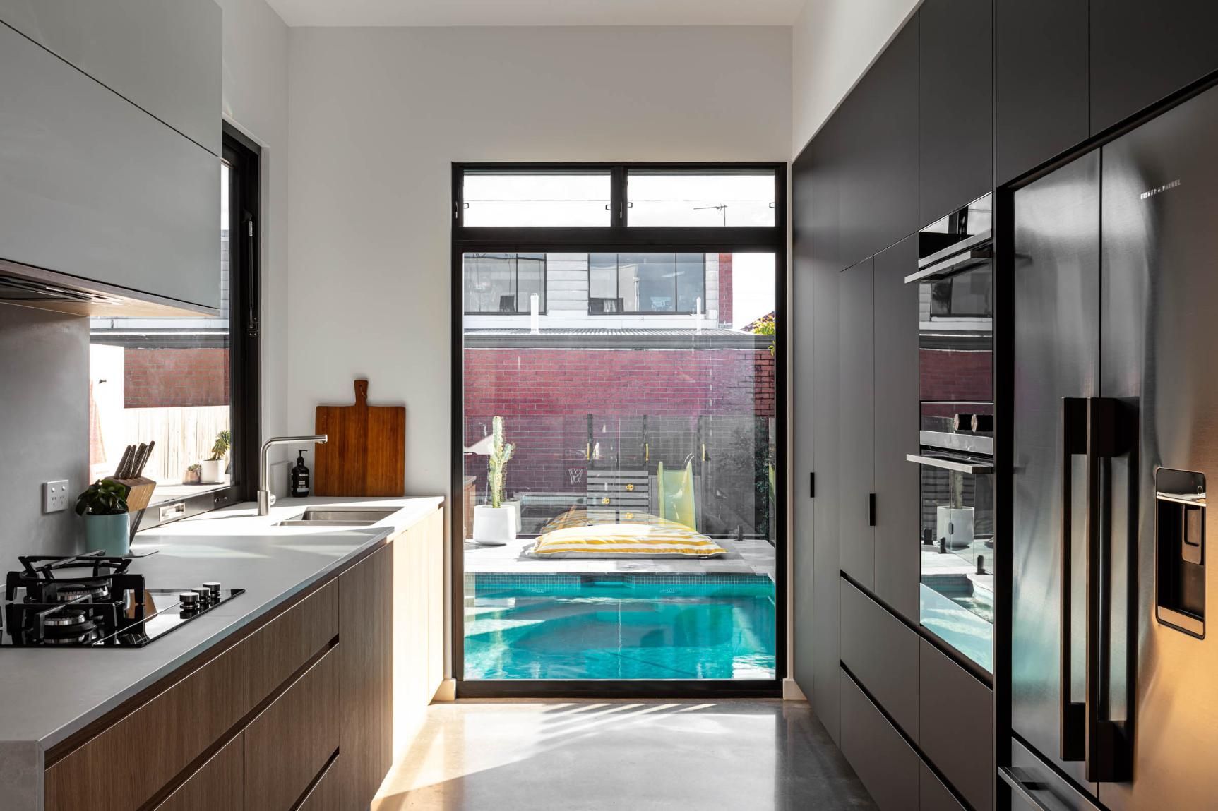 A Kitchen with A Sliding Glass Door Leading to A Swimming Pool — Goode By Design in Unanderra, NSW