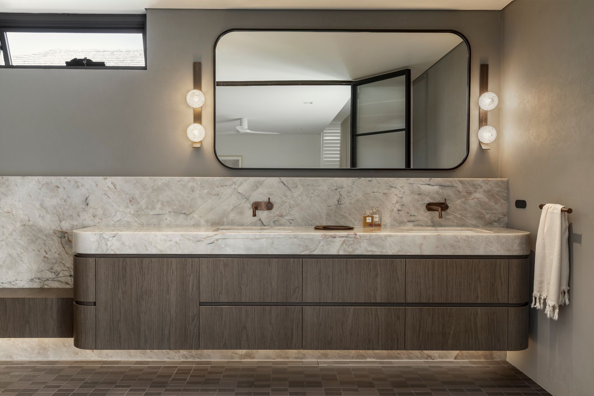 Modern bathroom vanity with double sinks, large mirror, wood cabinets, and neutral stone finishes