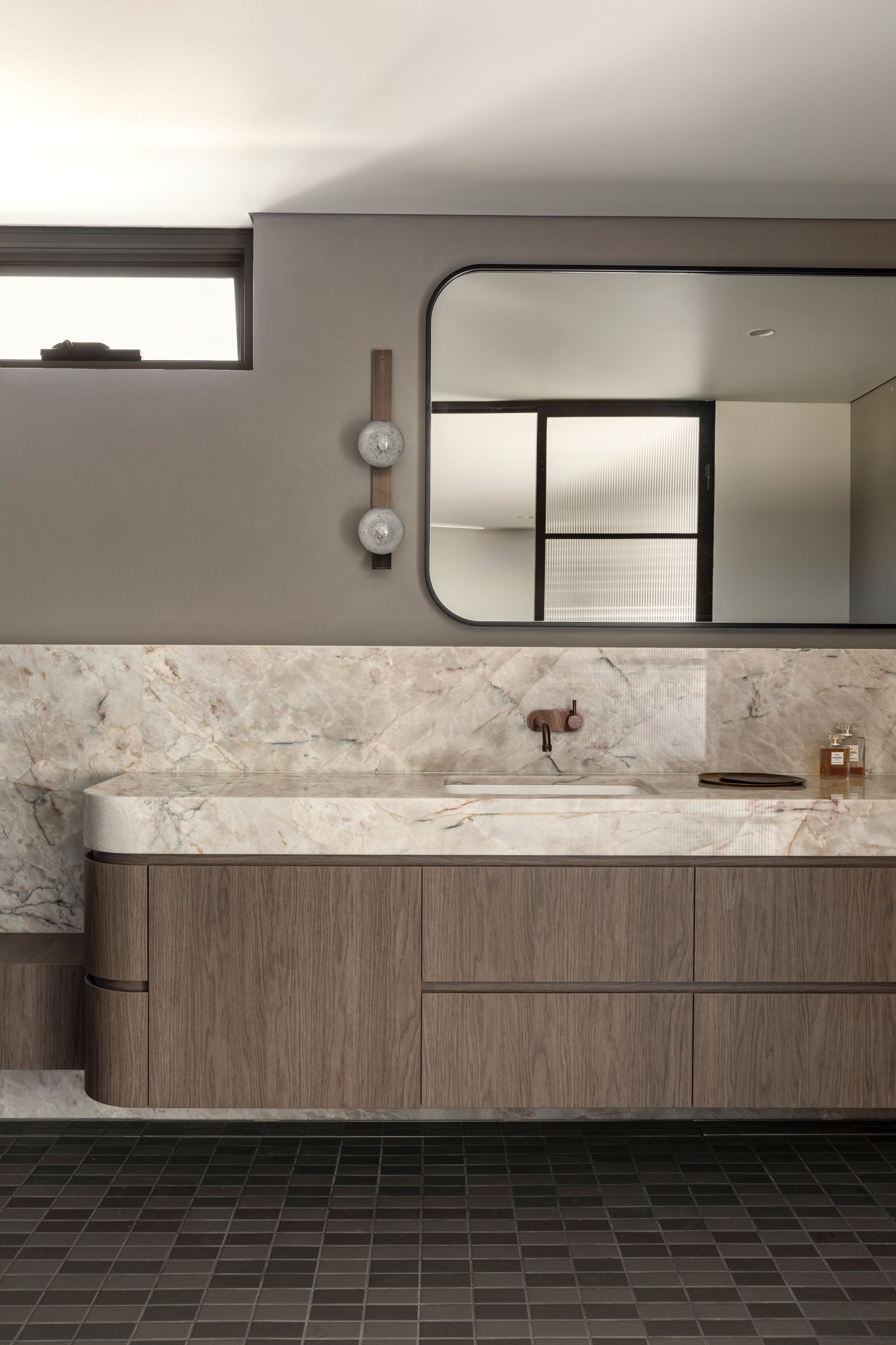 Modern bathroom vanity with mirror, wall lights, and marble countertop in neutral tones