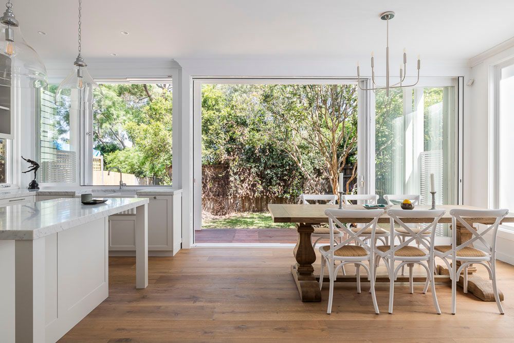 A dining room with a table and chairs and a kitchen bench — Goode By Design in Unanderra, NSW