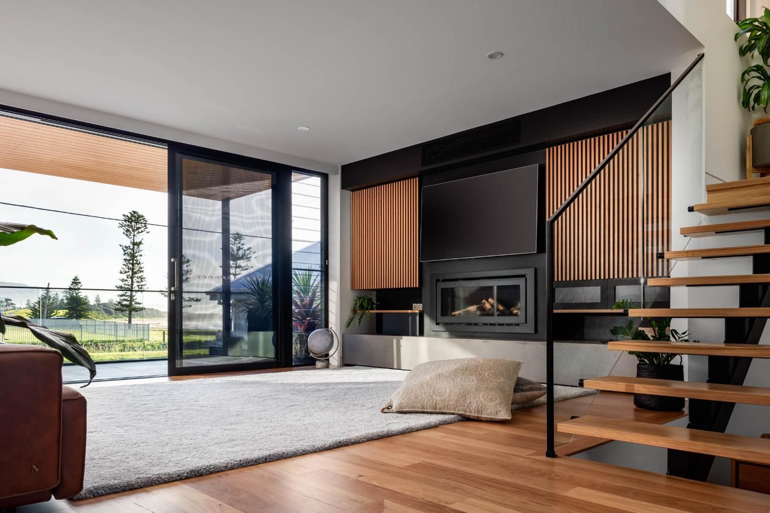 A Living Room with A Fireplace and Stairs Leading up To the Second Floor — Goode By Design in Unanderra, NSW