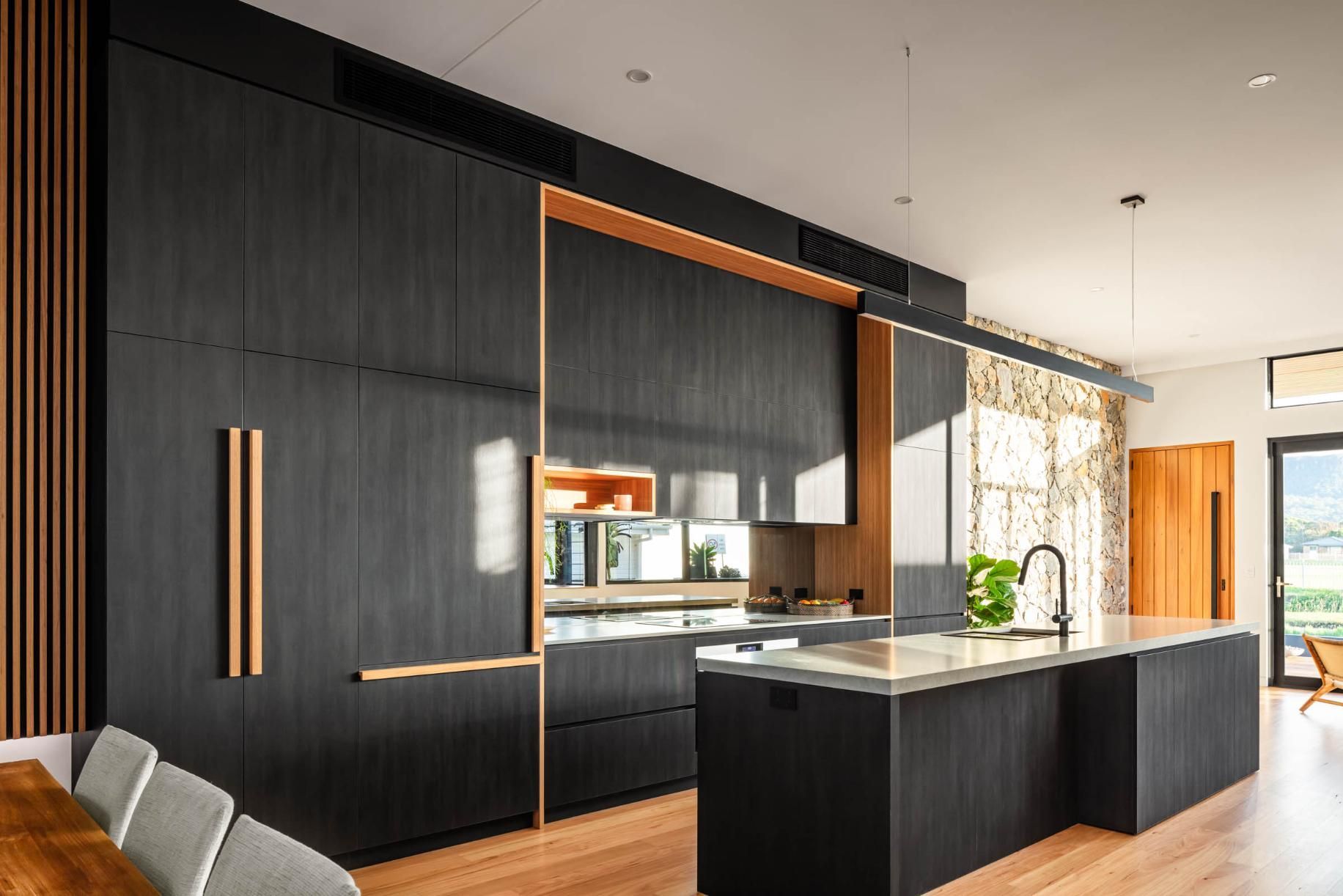 A Kitchen with Black Cabinets and A Large Island in The Middle of The Room — Goode By Design in Unanderra, NSW
