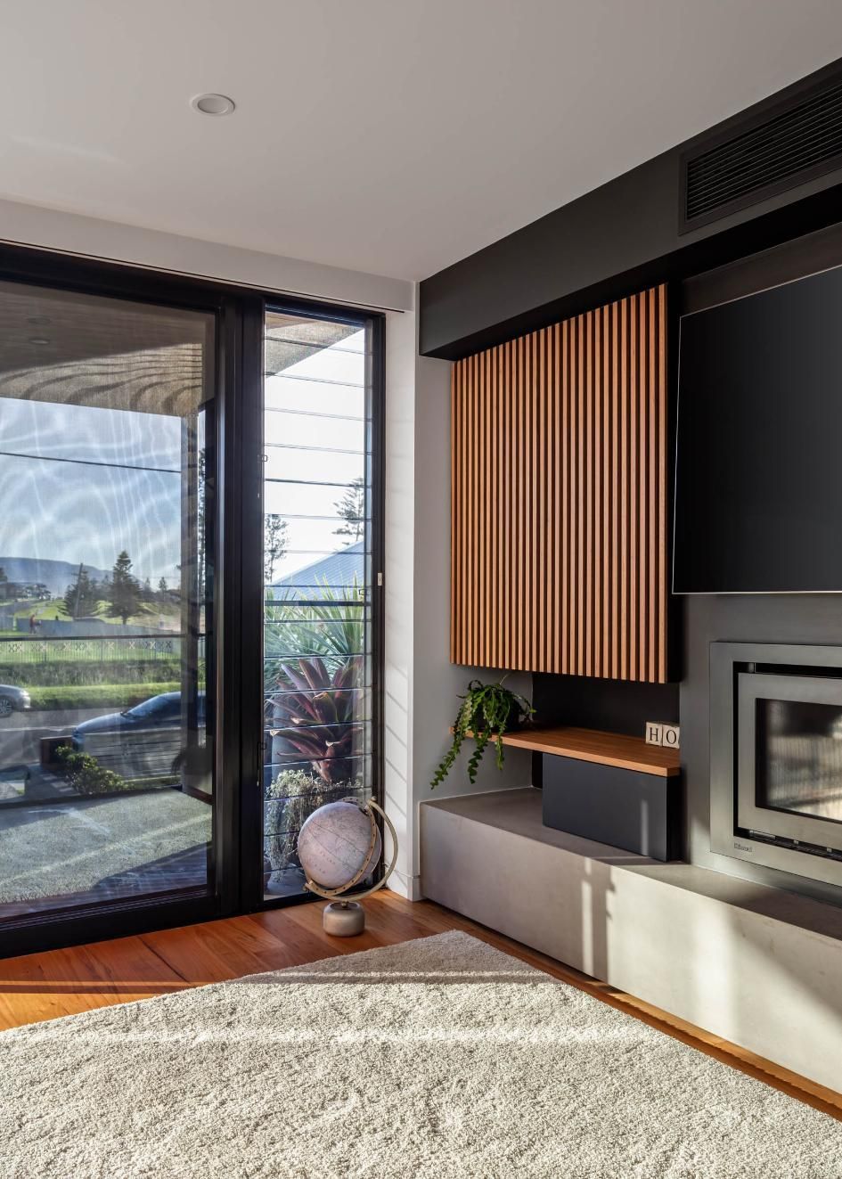 A Living Room with A Fireplace, Television, and Sliding Glass Doors — Goode By Design in Unanderra, NSW