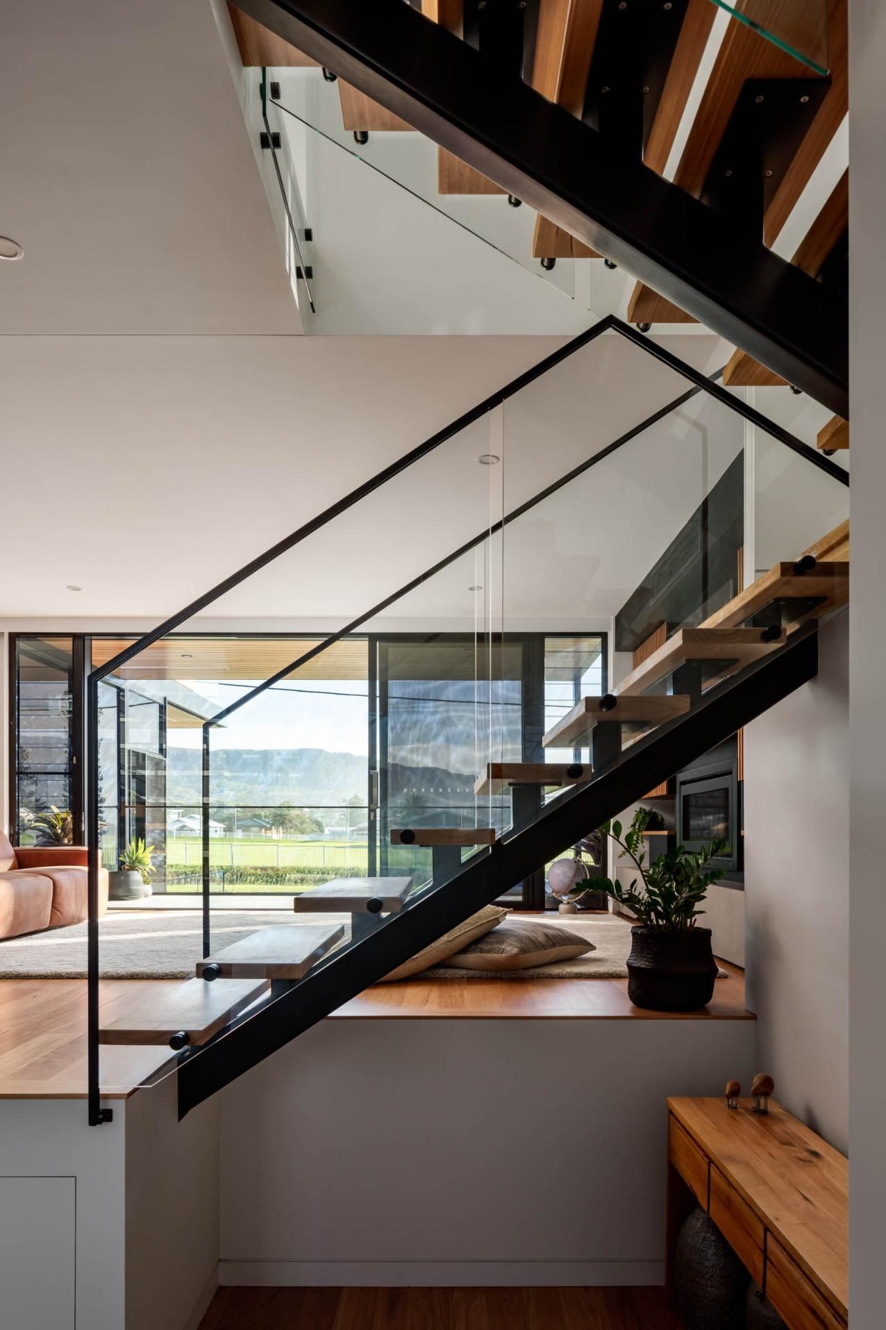 A Modern Staircase with A Glass Railing in A House — Goode By Design in Unanderra, NSW