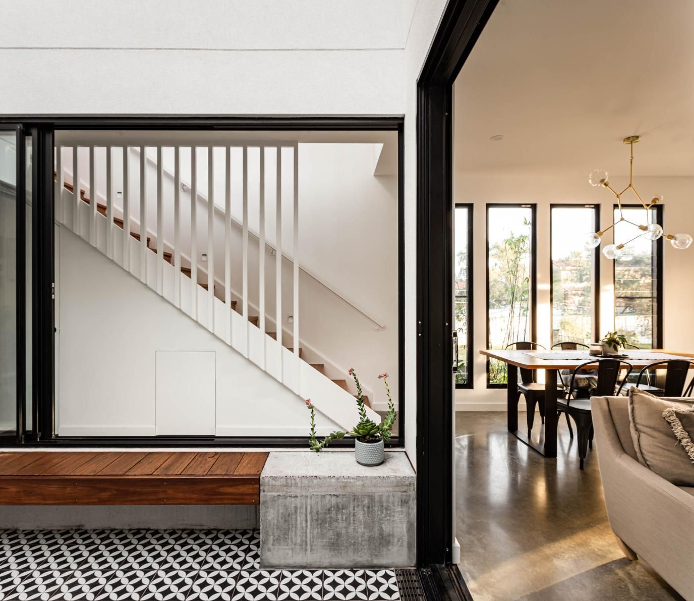Modern home interior with stairs visible through window, dining room, and living room. — Goode By Design in Unanderra, NSW