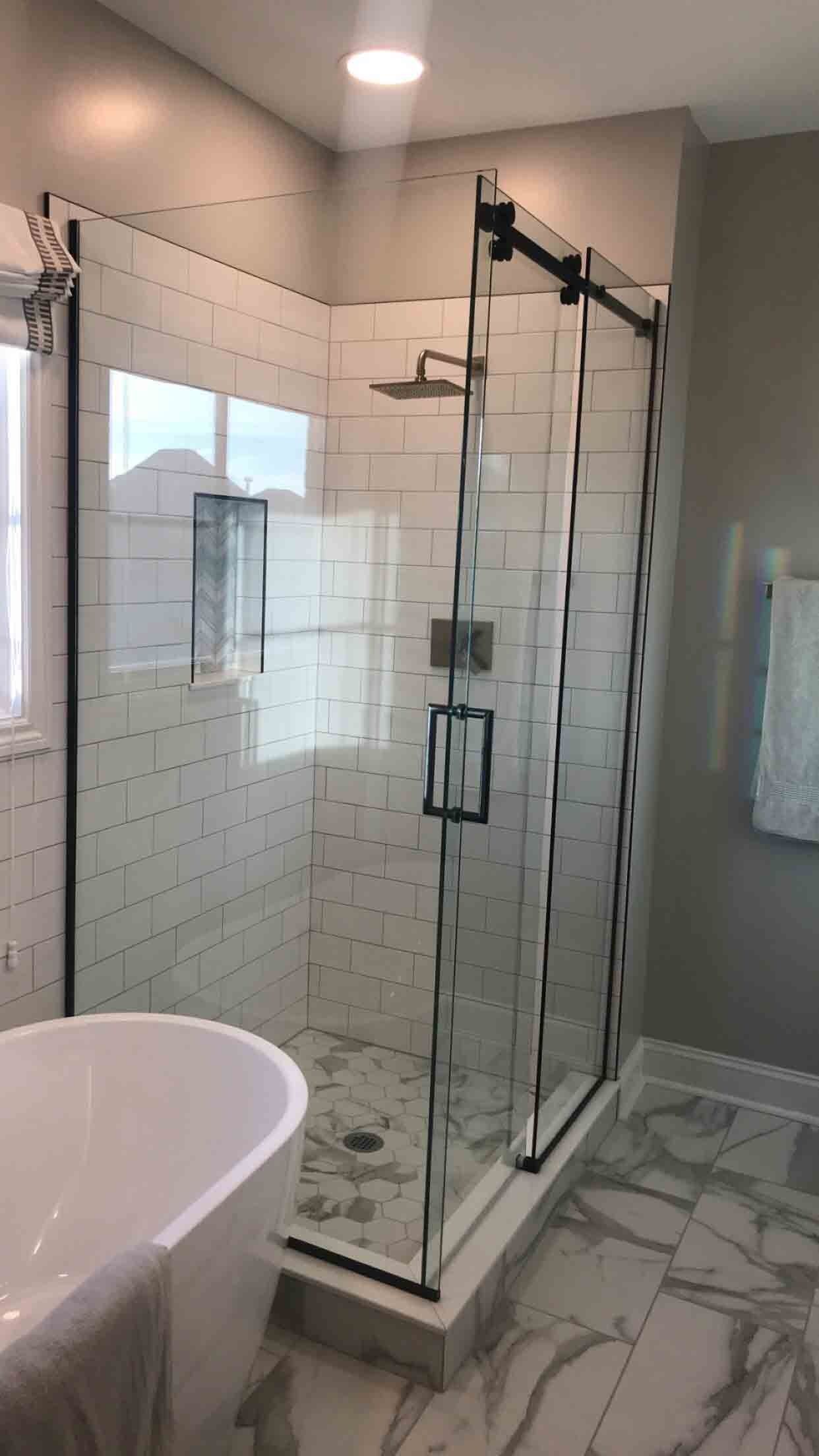 Modern bathroom with a glass shower, white subway tiles, and a freestanding tub.