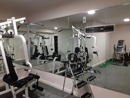 Home gym with workout machines, mirrors, and a person in the reflection.