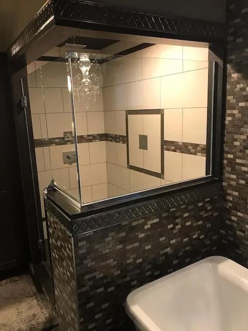 Bathroom with glass-enclosed shower, mosaic tile wall, and white bathtub.