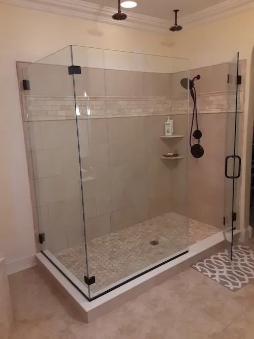 Glass shower enclosure with brown fixtures and tan tile.