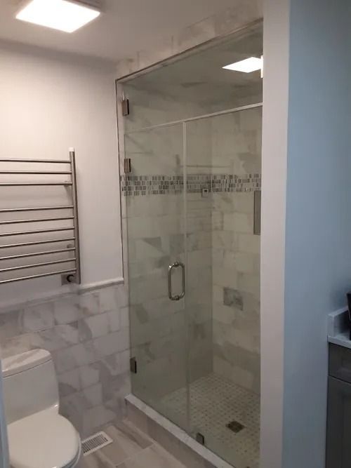 A modern bathroom with a glass shower enclosure, a heated towel rack, and a toilet.