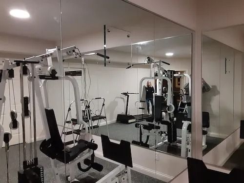 Home gym with workout machines and a large wall mirror.