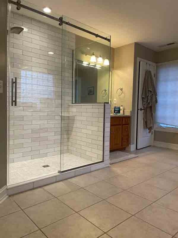 Modern bathroom with a glass shower, subway tile, vanity, and tan walls.