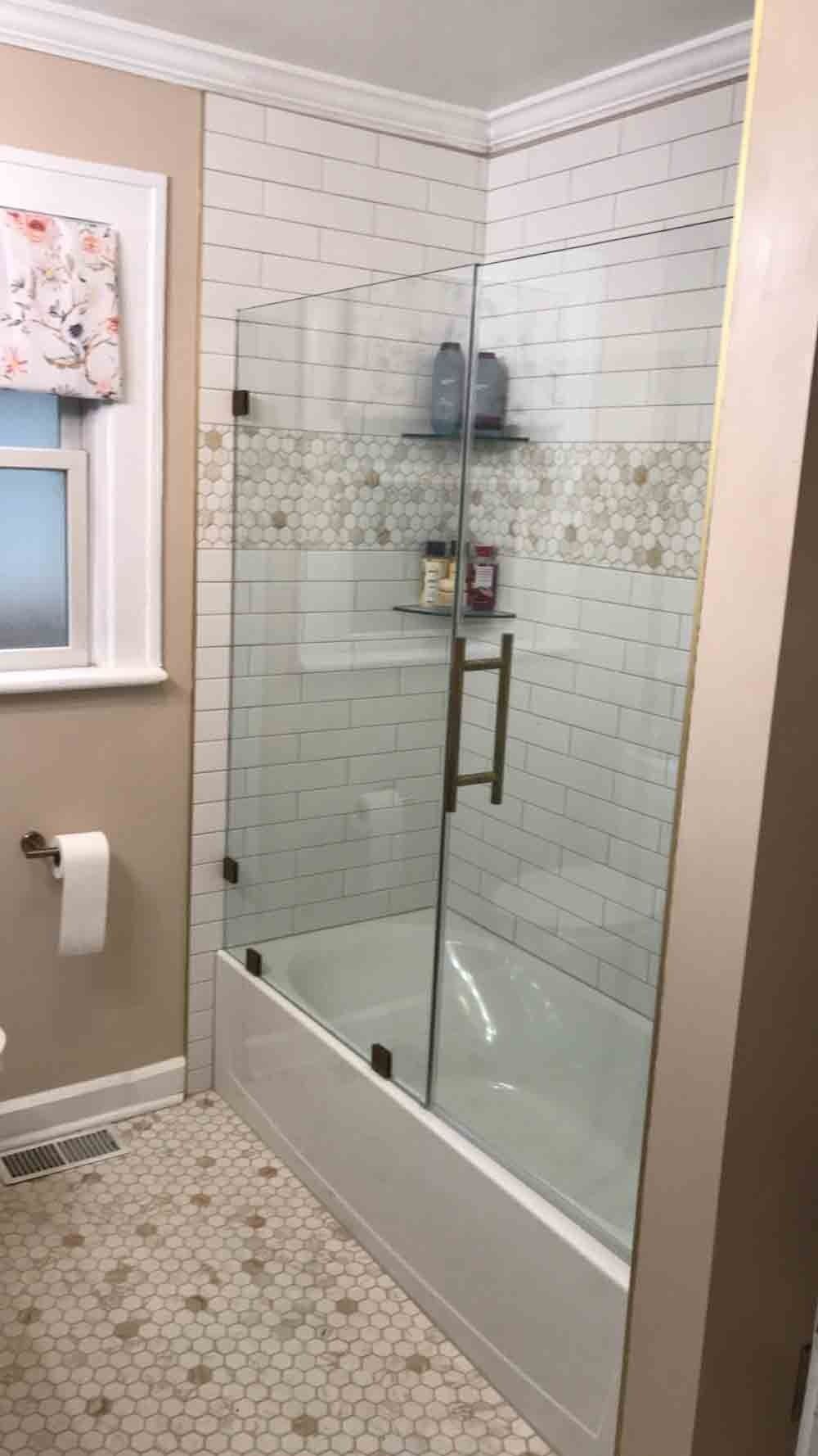 Bathroom with tiled walls, shower enclosure, and bathtub. Beige walls, white and patterned tiles.