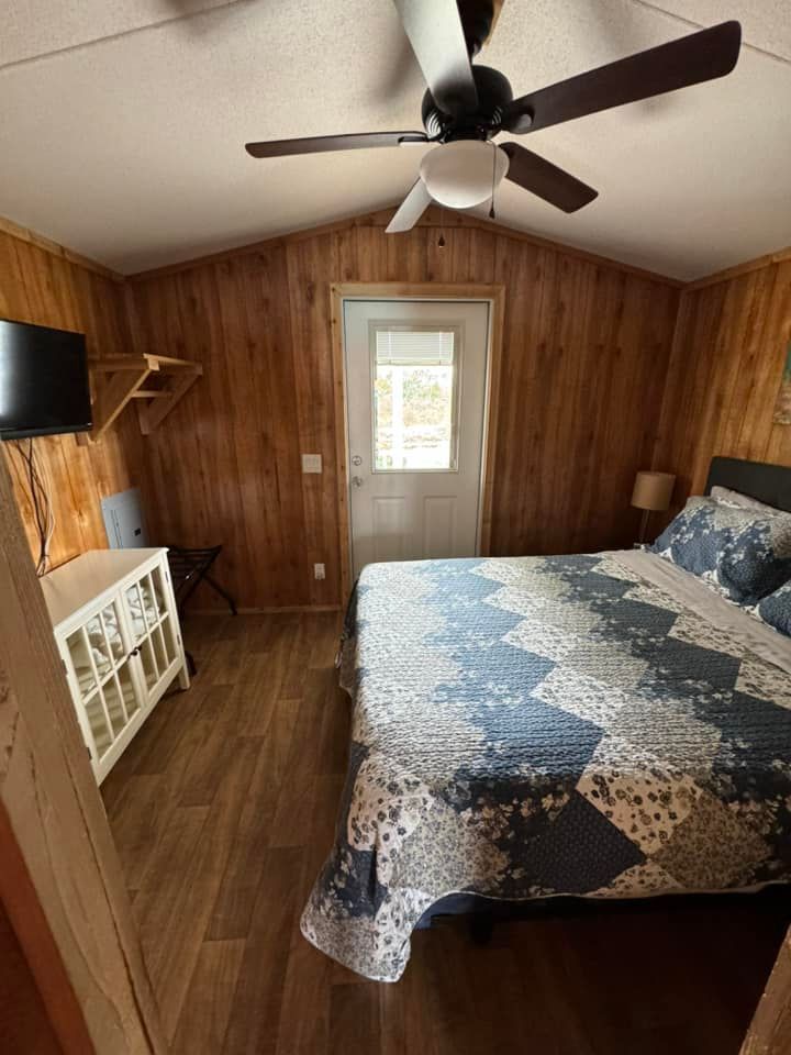A bedroom with a bed , ceiling fan and television.