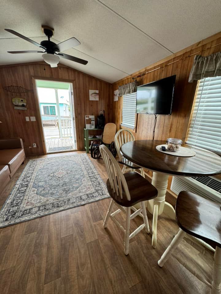 A living room with a table and chairs and a ceiling fan.