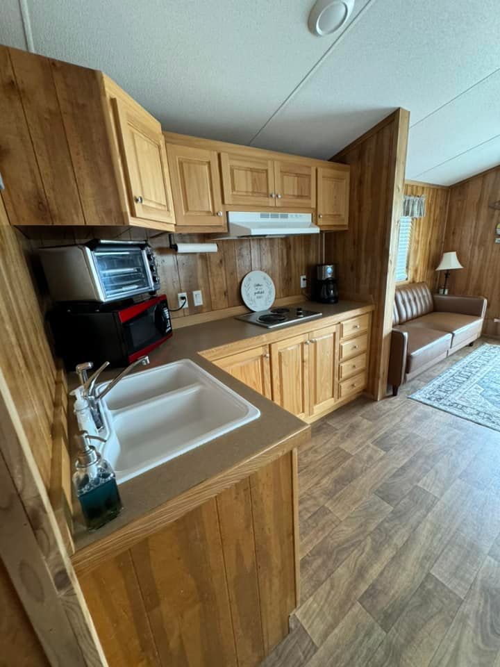A kitchen in a mobile home with wooden cabinets and a sink.