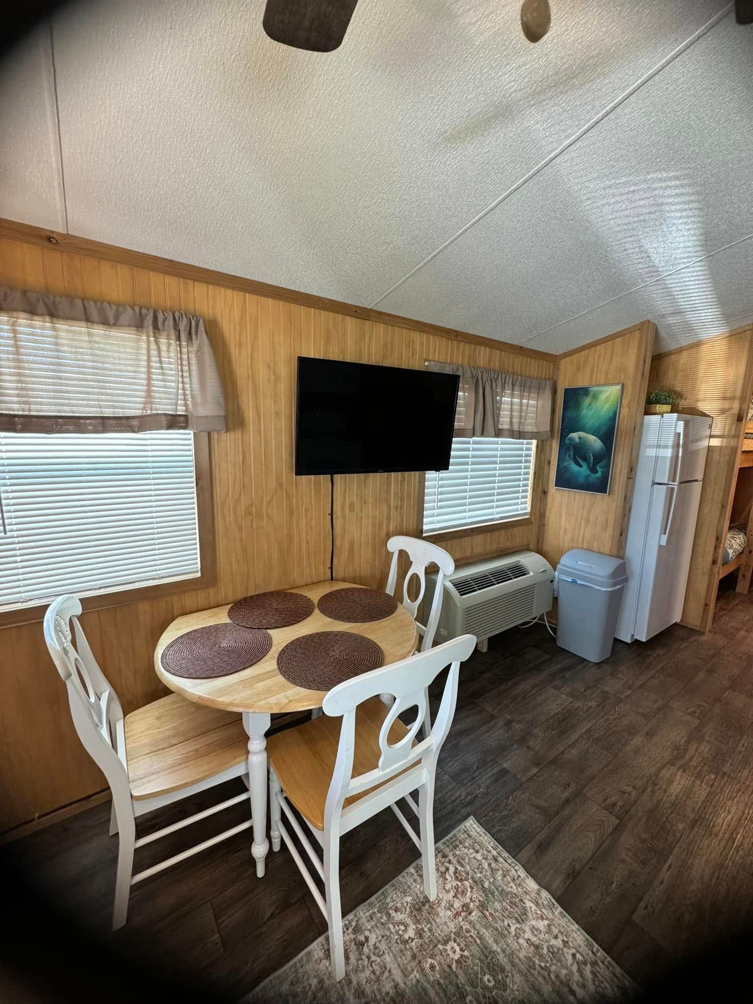 A cozy kitchen and dining area in a mobile home, featuring modern appliances and a small dining table with chairs.
