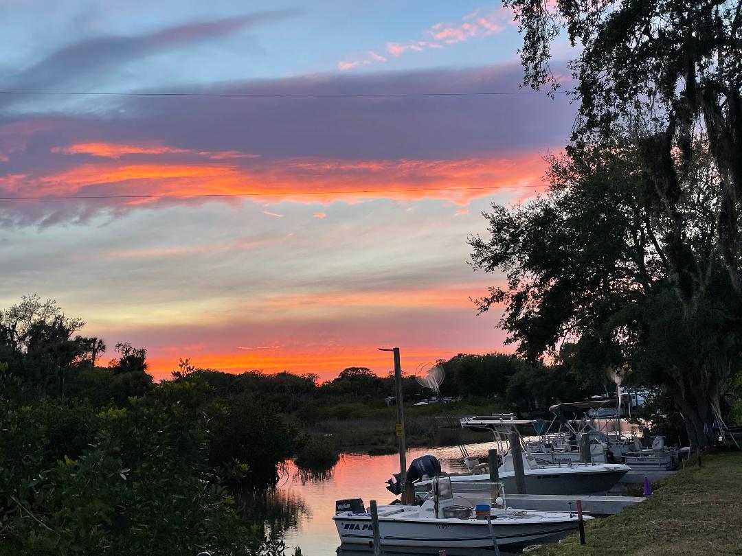 A sunset over a body of water with boats docked.