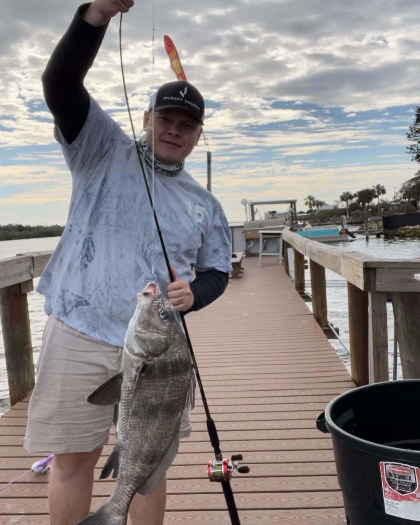 A man is holding a large fish on a dock.