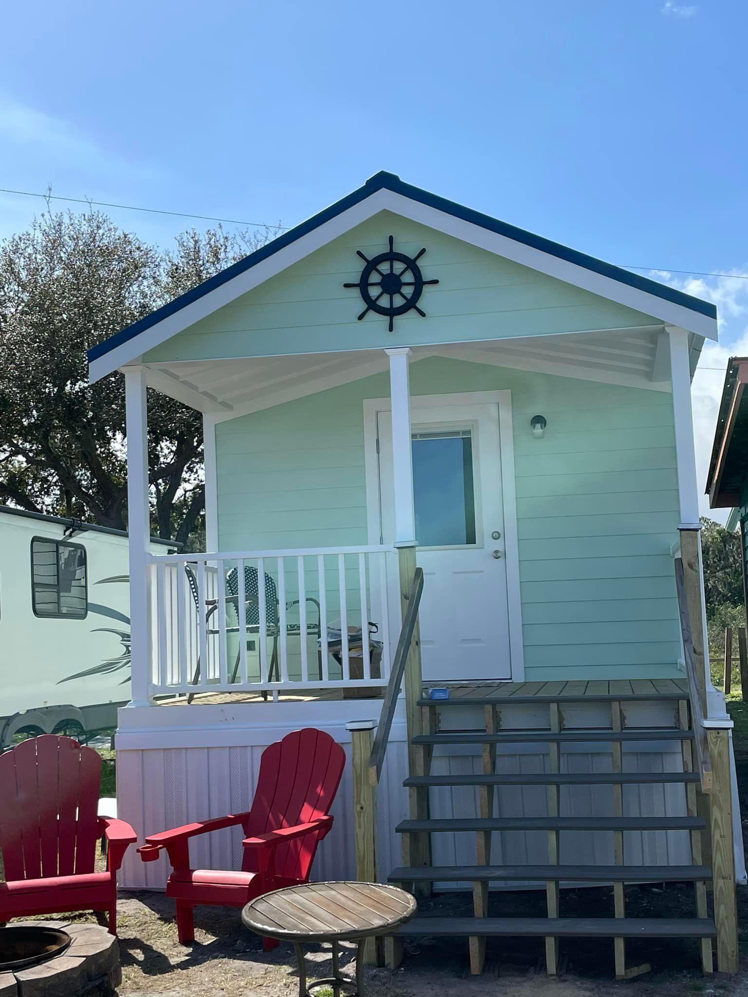 A small house with a porch , stairs and red chairs.