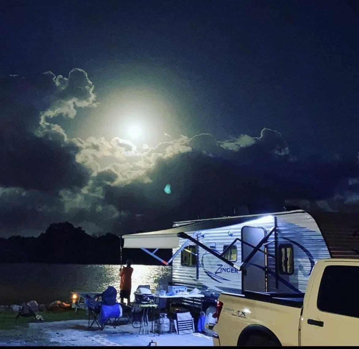 A truck is parked in front of a rv at night