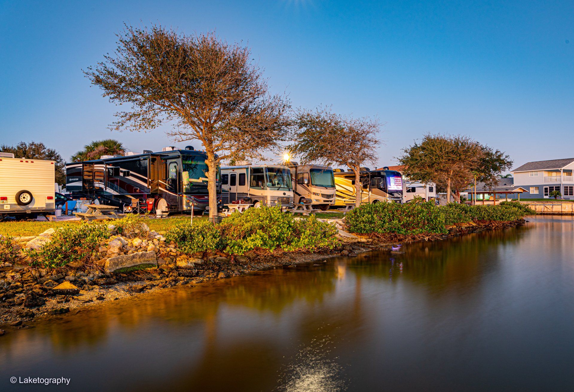 A row of rvs parked next to a body of water.