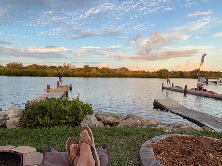 person is laying on a chair next to a lake.