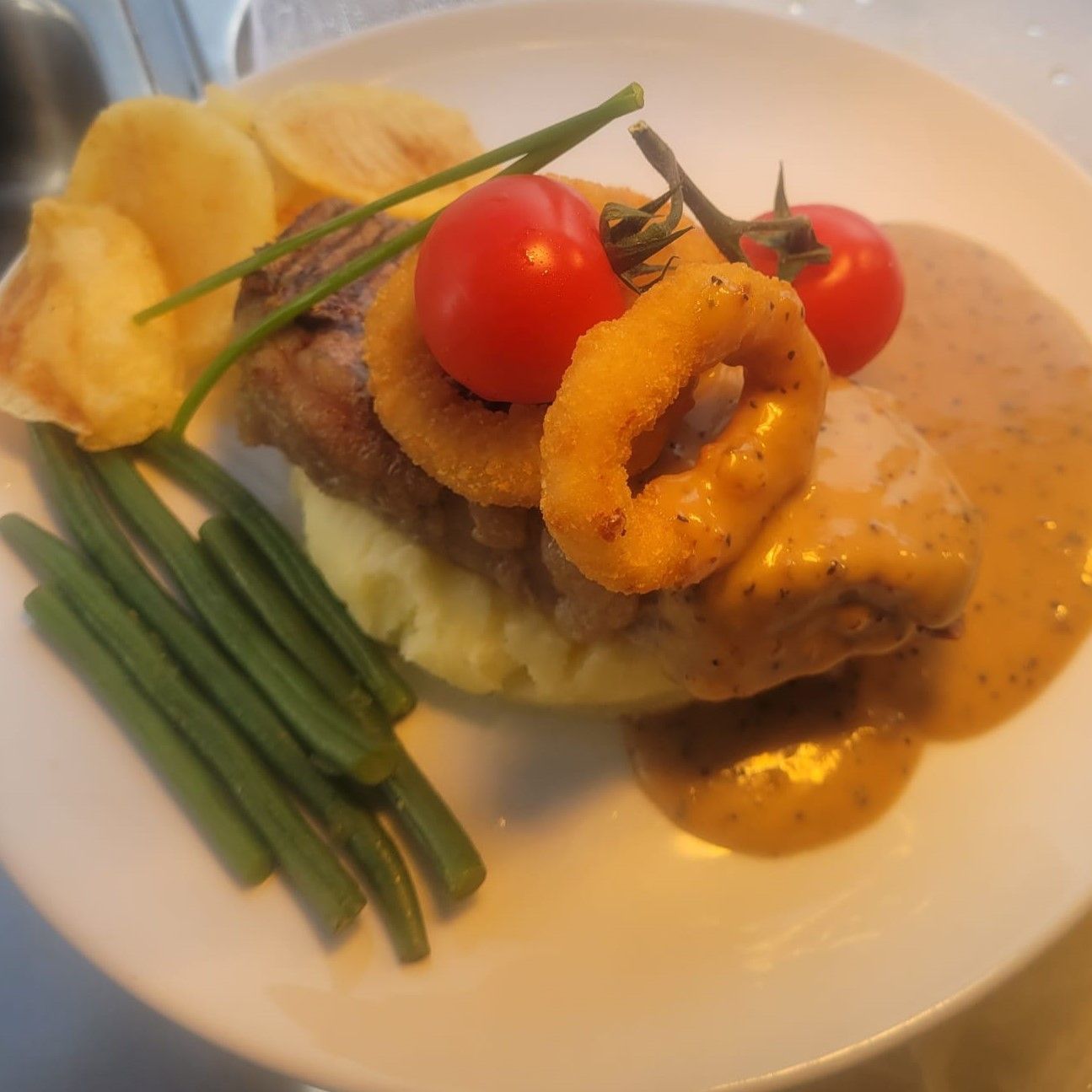 A plate of food with green beans and tomatoes on top