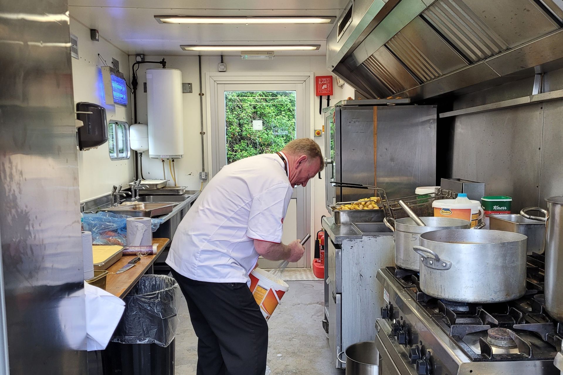 A man is standing in a kitchen looking at his phone.