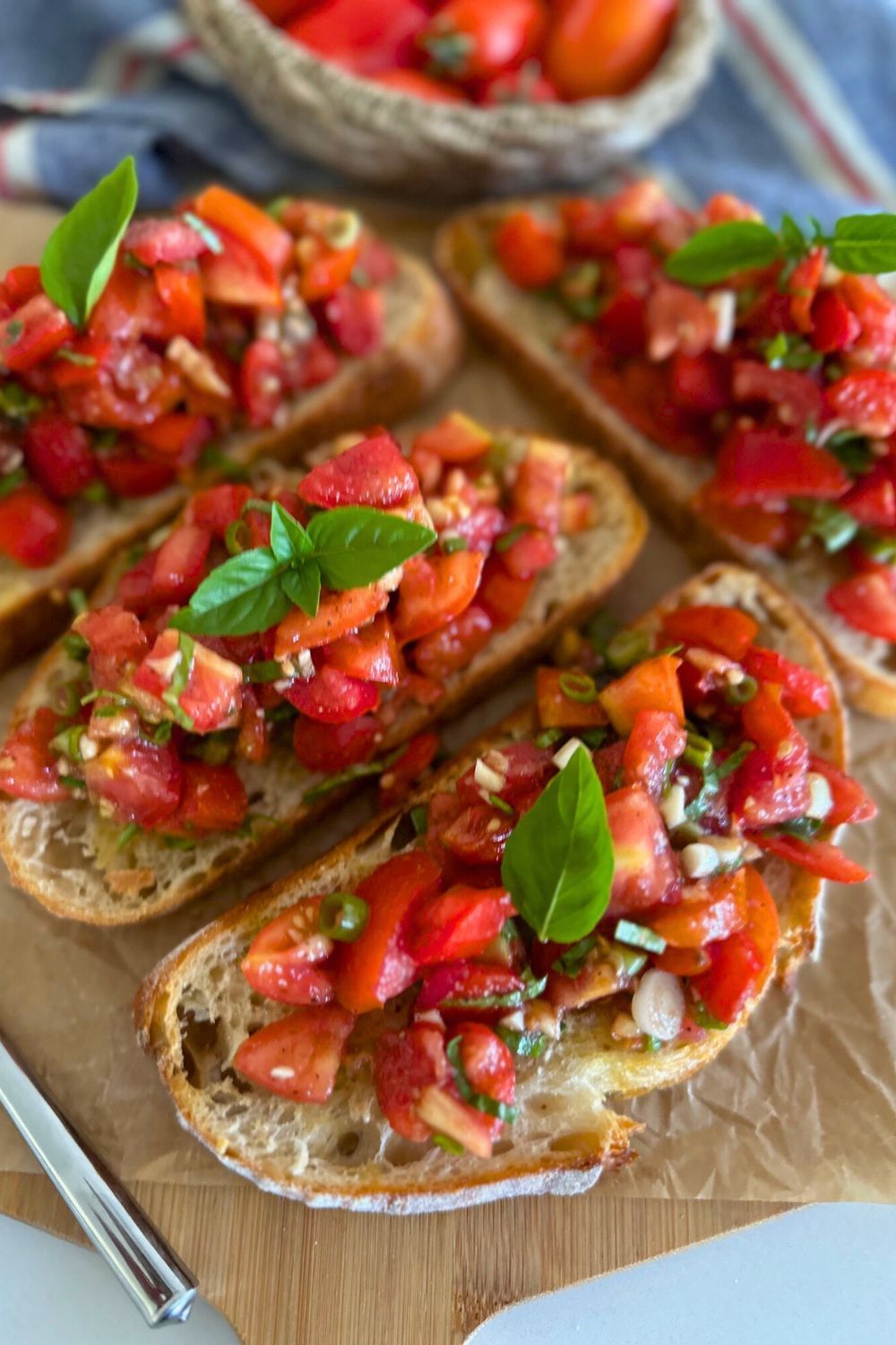 A cutting board topped with slices of bread topped with tomatoes and basil.