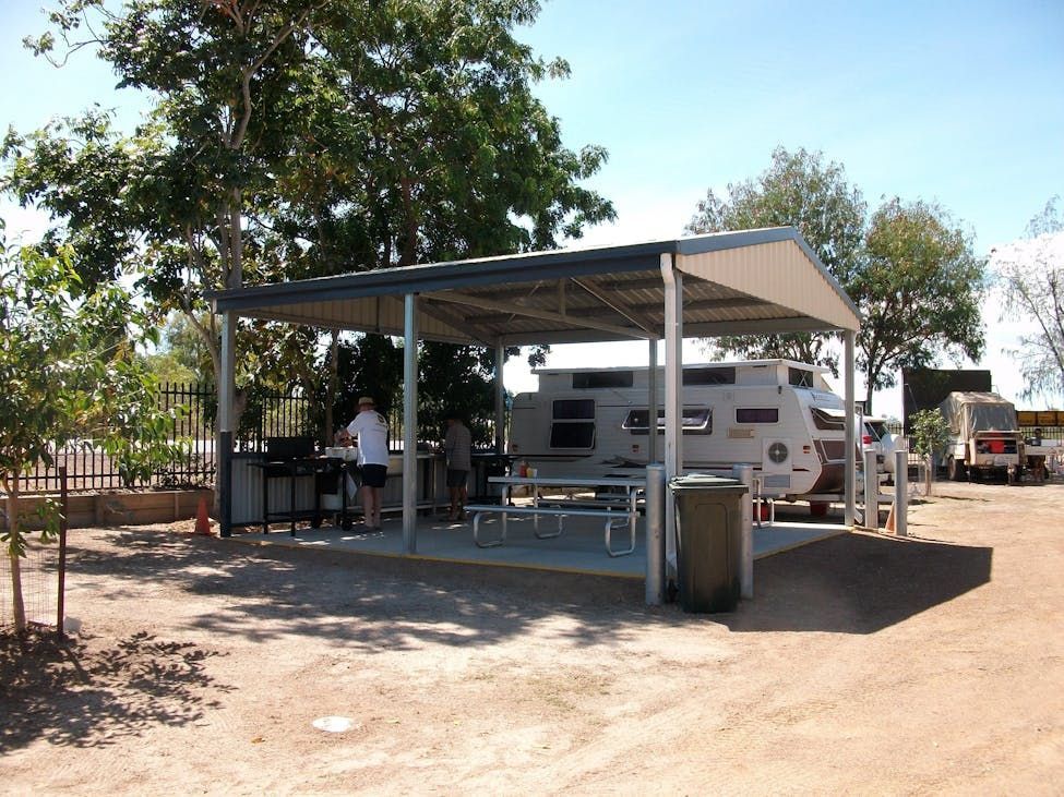 Picnic Shelter With Caravan, Picnic Tables, and People Grilling Outdoors — Karumba Point Holiday Tourist Park in Karumba, QLD
