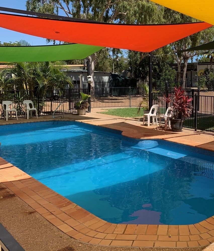 Swimming Pool With Blue Water, Surrounded by Brick and Shaded by Colorful Canopies — Karumba Point Holiday Tourist Park in Karumba, QLD