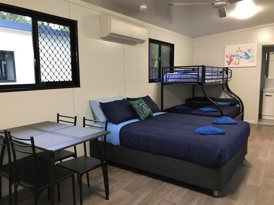 Bedroom With Bunk Bed, Double Bed, Table, Chairs, Ac Unit, and Painting — Karumba Point Holiday Tourist Park in Karumba, QLD