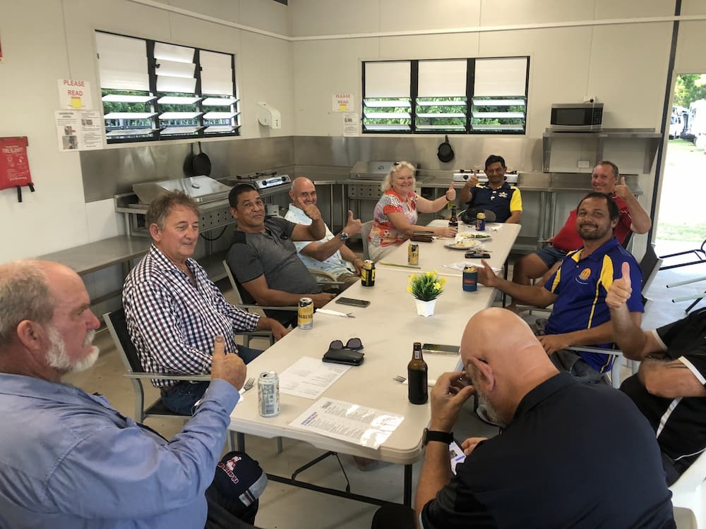 A Group of People Sitting Around a Table Inside, Some Are Holding Drinks and Giving Thumbs Up — Karumba Point Holiday Tourist Park in Karumba, QLD