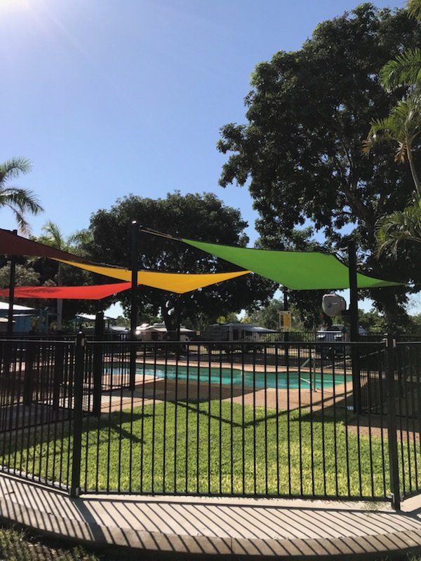 Pool Area With Shade Sails in Red, Yellow, and Green — Karumba Point Holiday Tourist Park in Karumba, QLD