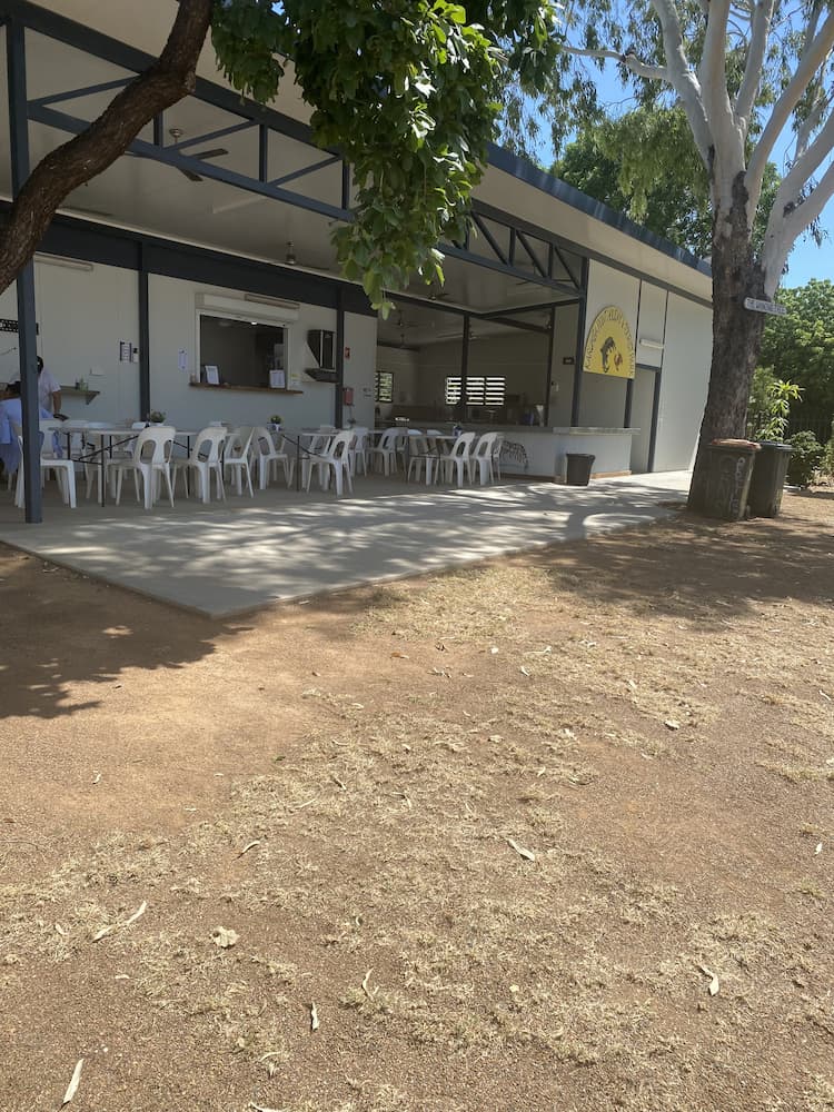 A White Outdoor Cafe With Plastic Chairs and Tables Under a Shaded Awning on a Sunny Day — Karumba Point Holiday Tourist Park in Karumba, QLD