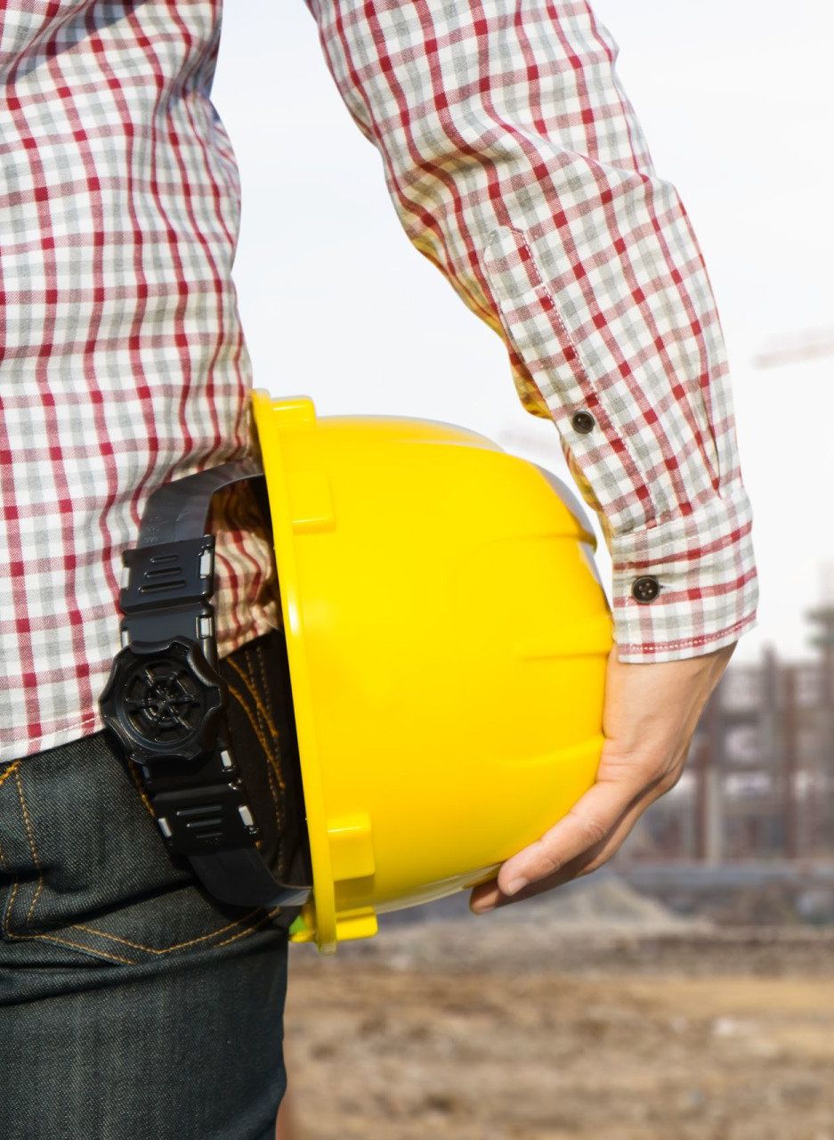 Un hombre con una camisa a cuadros sostiene un casco amarillo.