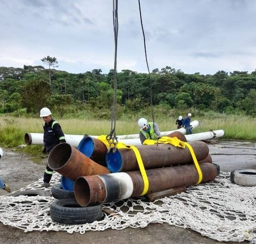 Los trabajadores, utilizando una grúa, ataron tubos de acero con correas amarillas y colocaron una red de seguridad debajo.