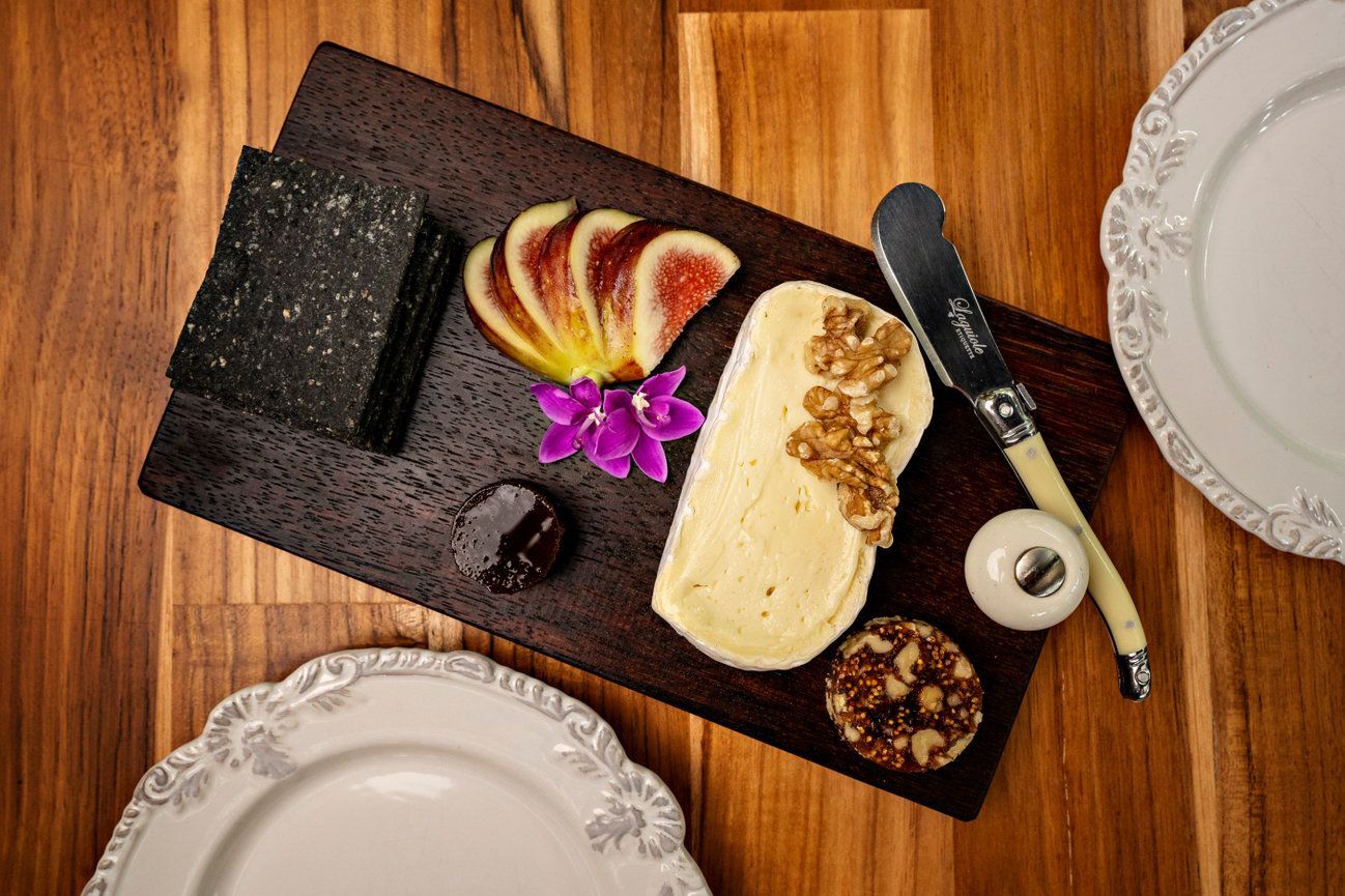 A wooden cutting board topped with cheese , fruit and nuts.