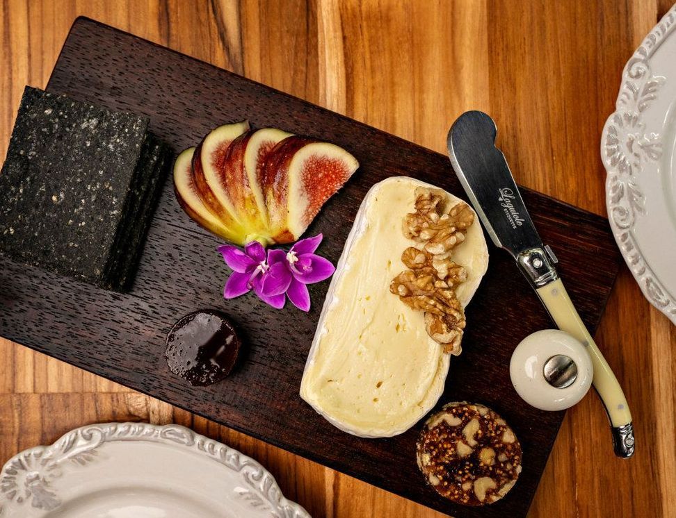 A wooden cutting board topped with cheese nuts and figs