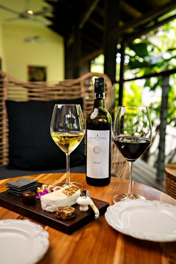 A bottle of wine and two glasses of wine are on a wooden table.