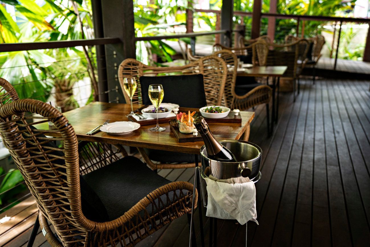 A table with two glasses of wine and a bucket of champagne on it.