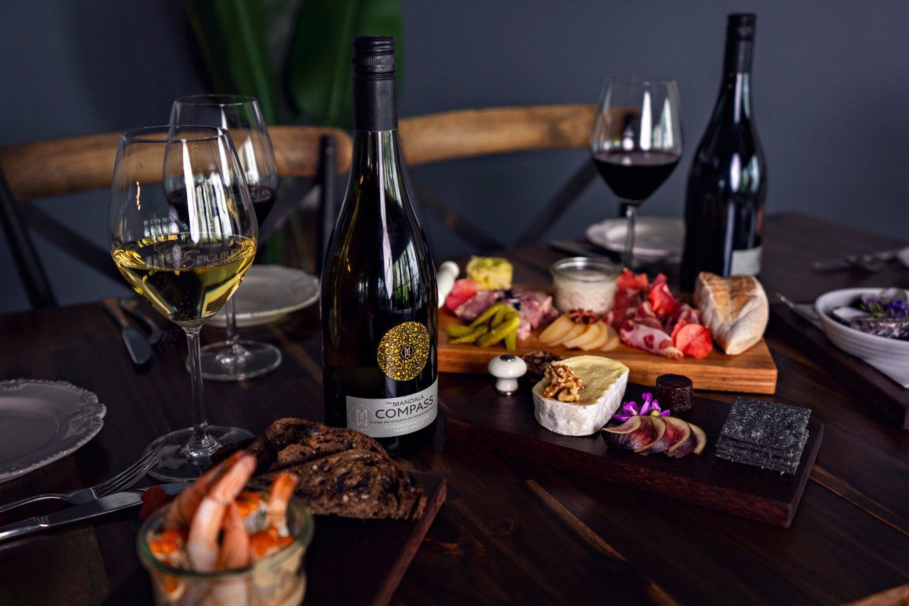 A wooden table topped with a variety of food and wine glasses.