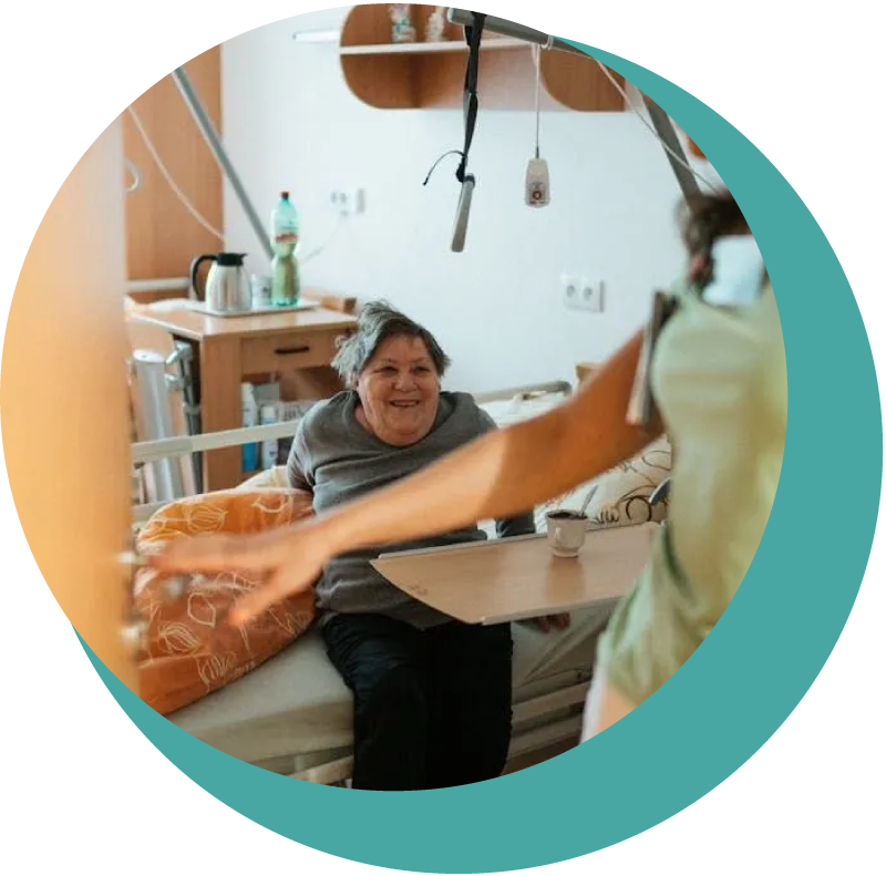 A woman is sitting in a hospital bed talking to another woman