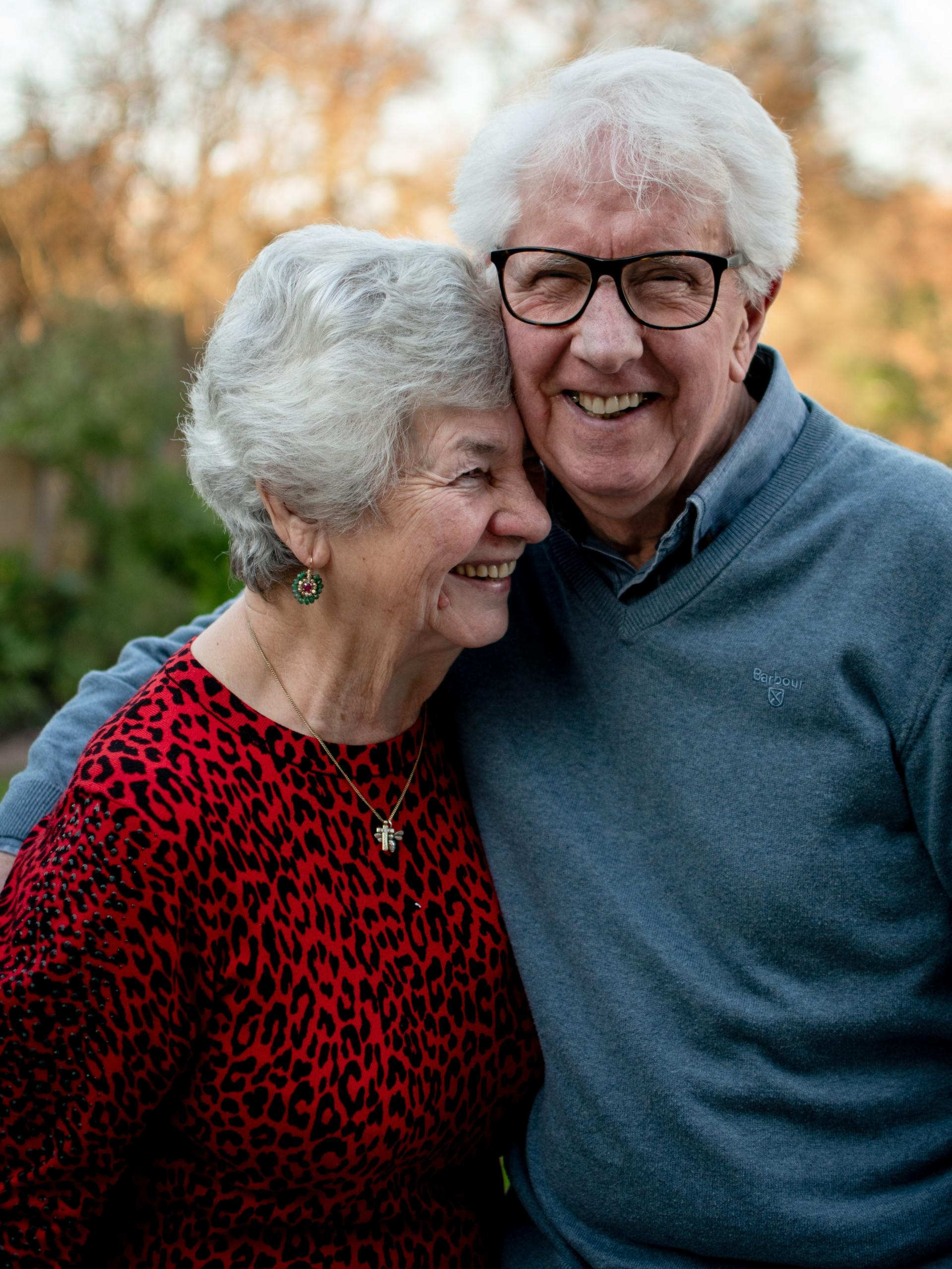 A man and a woman are hugging each other and smiling for the camera.
