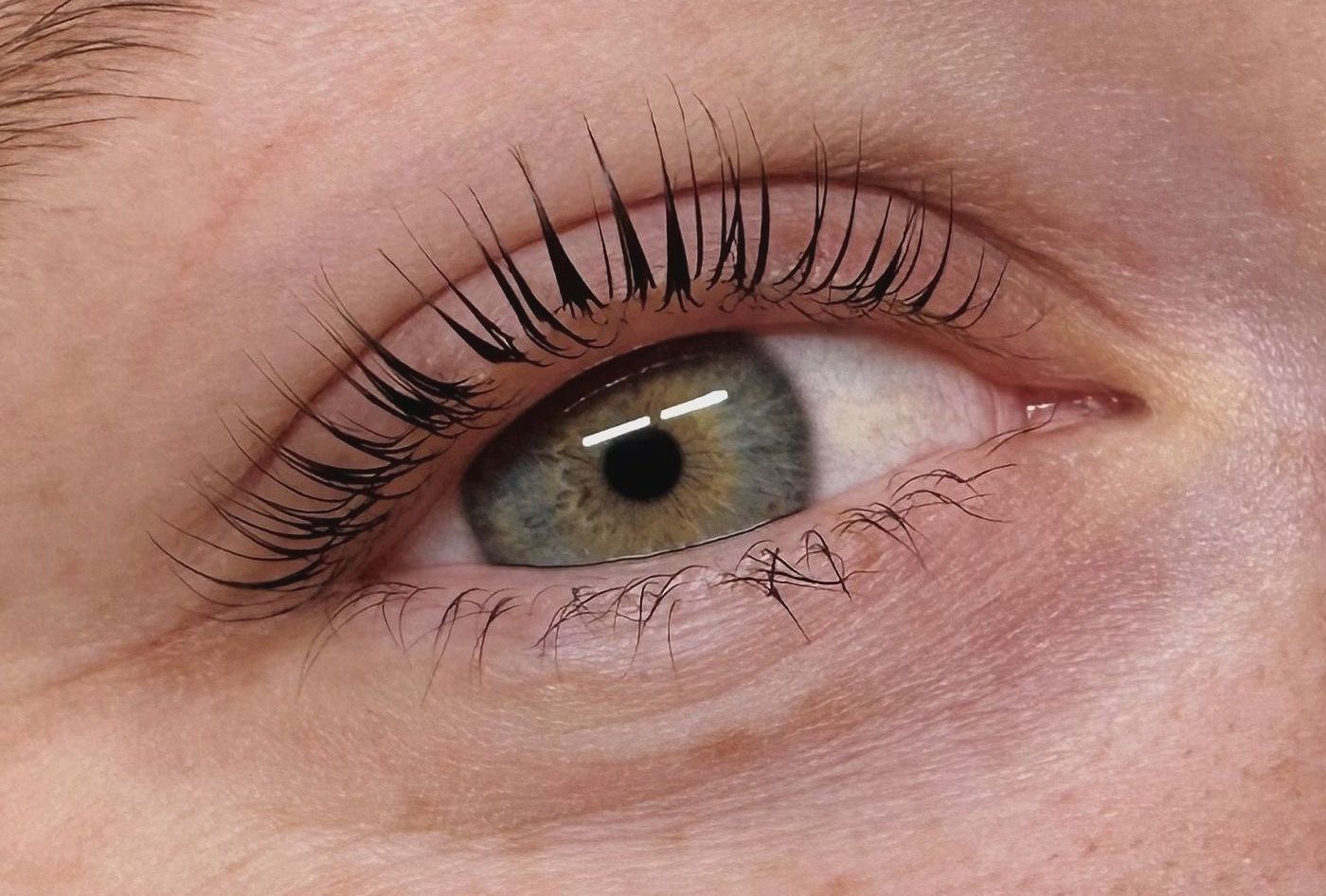 A close-up of a woman's green eye with long eyelashes. A close-up of a woman's green eye with long eyelashes.