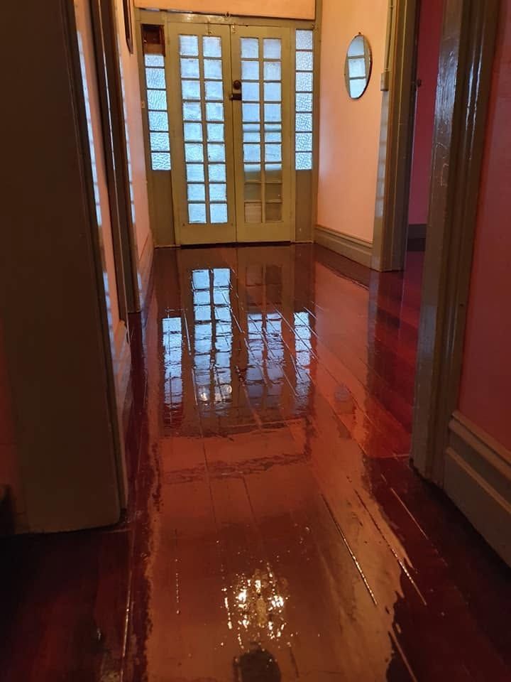 Hallway with glossy red wooden floor, cream walls, and glass-paneled French doors at the end.