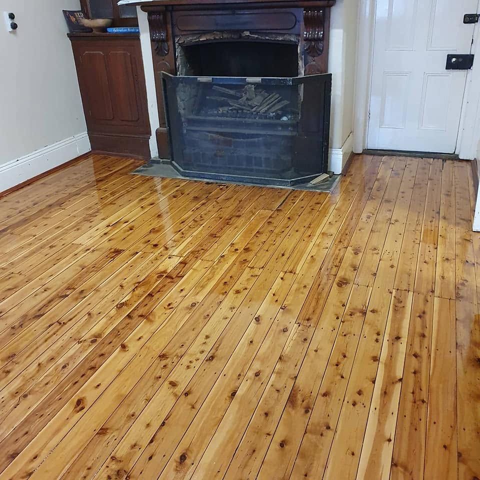 Shiny hardwood floor in an empty room with large bay windows and daylight reflections