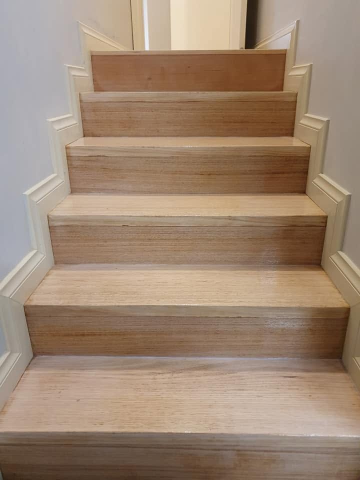 Carpeted indoor staircase with wooden treads and white trim, viewed from the bottom.