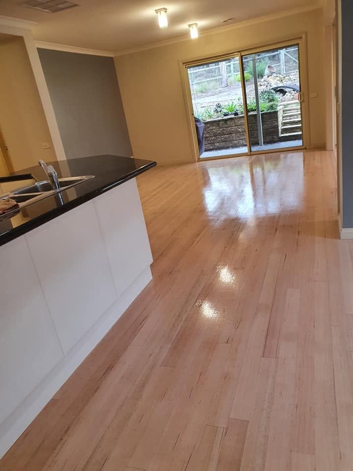 Empty modern kitchen and dining area with light wood floors and sliding glass doors to a patio